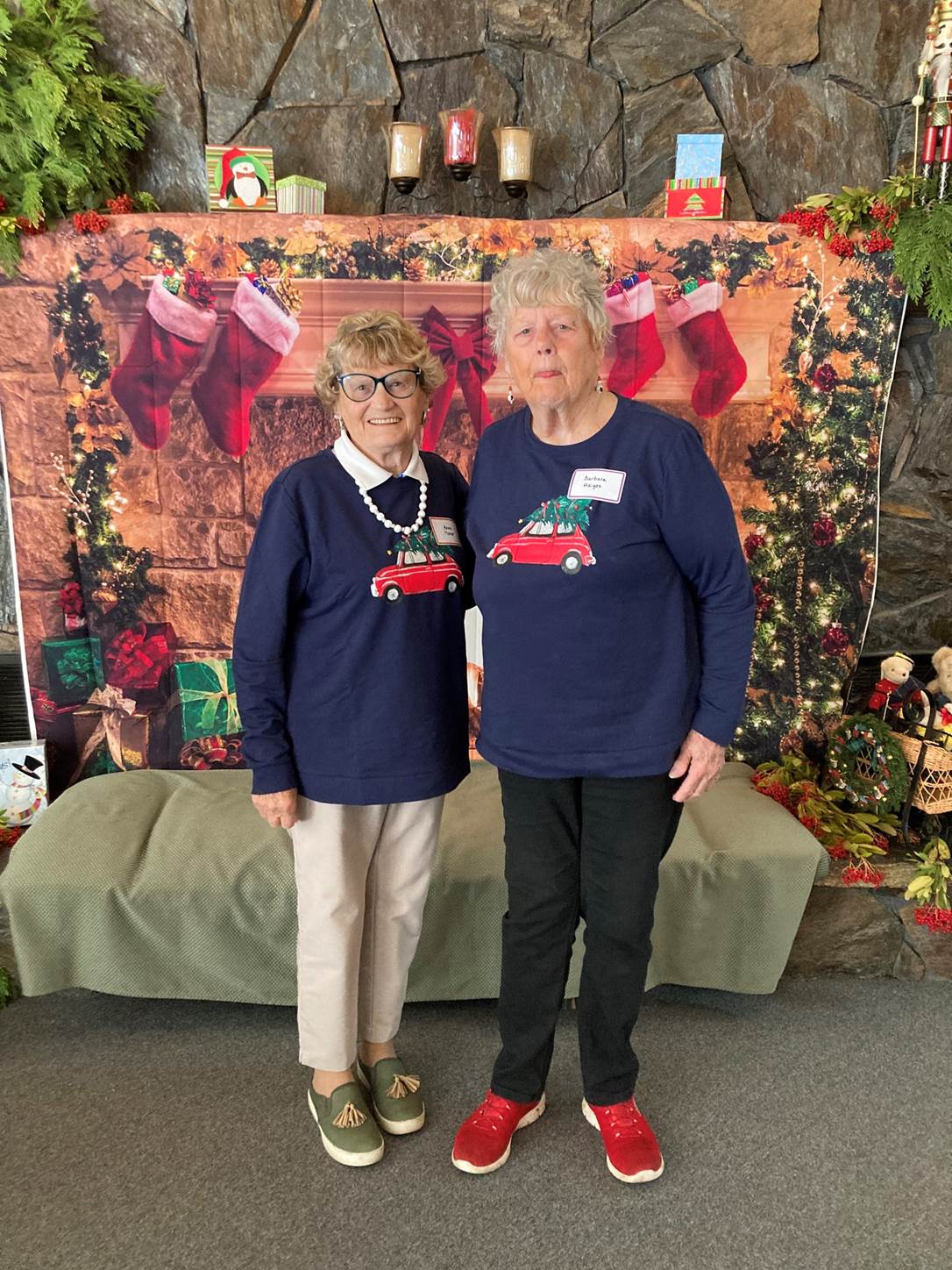 Two women standing in front of a christmas backdrop

Description automatically generated